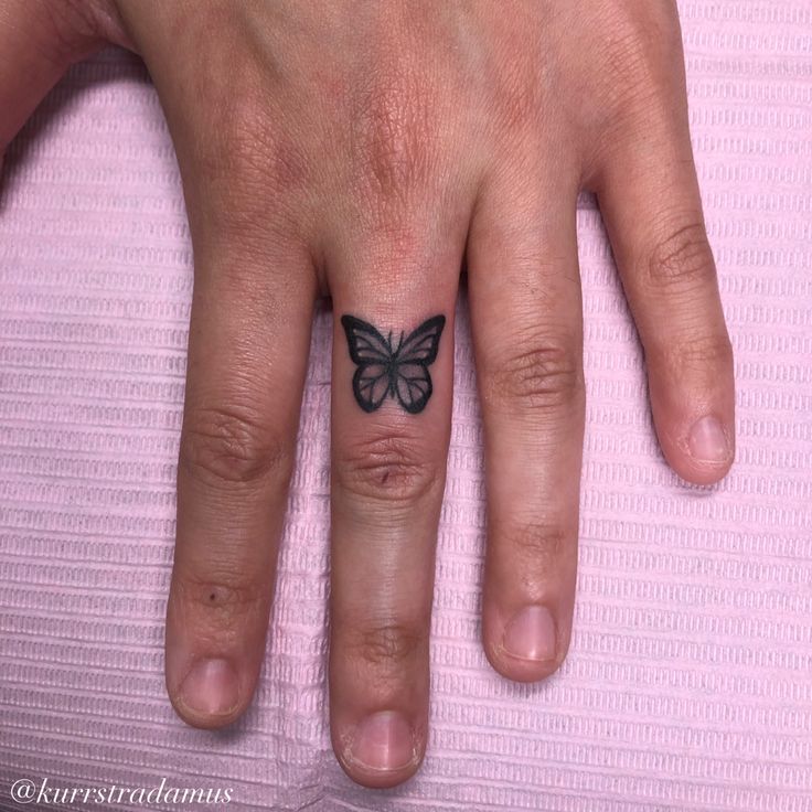 a woman's hand with a butterfly tattoo on her left ring finger and the other half of her fingers