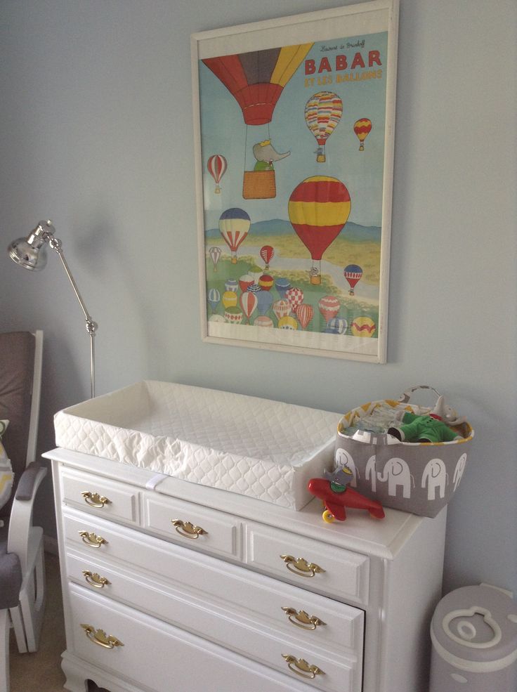 a baby's room with an elephant poster above the crib and toys on the dresser