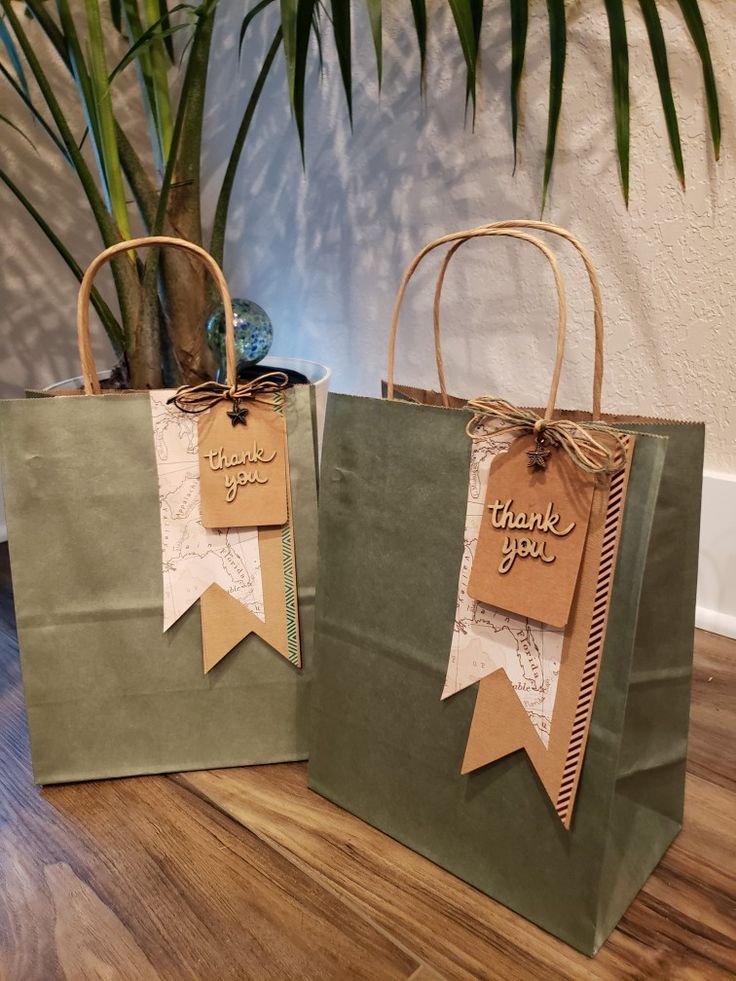 two bags with tags on them sitting next to a potted plant and a sign that says thank you