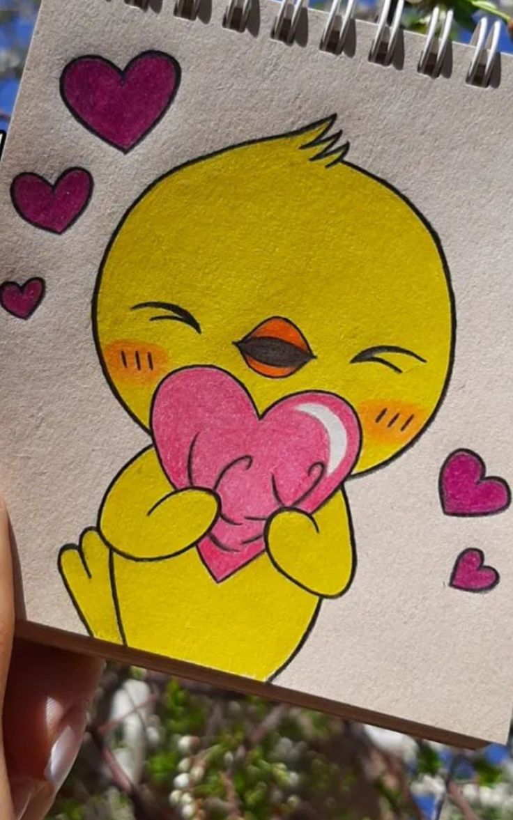 someone holding up a drawing of a baby chick with hearts on it's chest