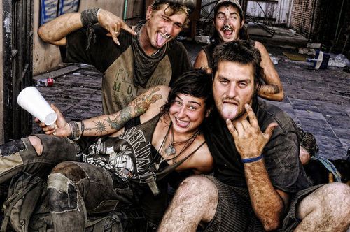 a group of young men sitting next to each other in front of a building with their mouths open