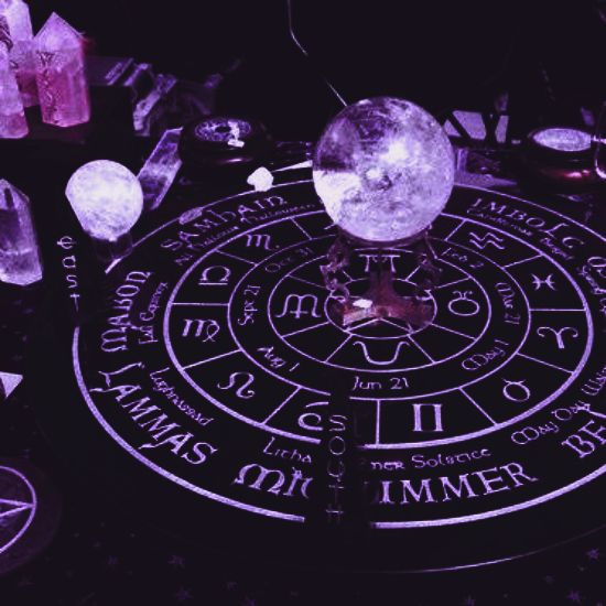 an astro wheel surrounded by crystal balls and other crystals on a table with purple lighting