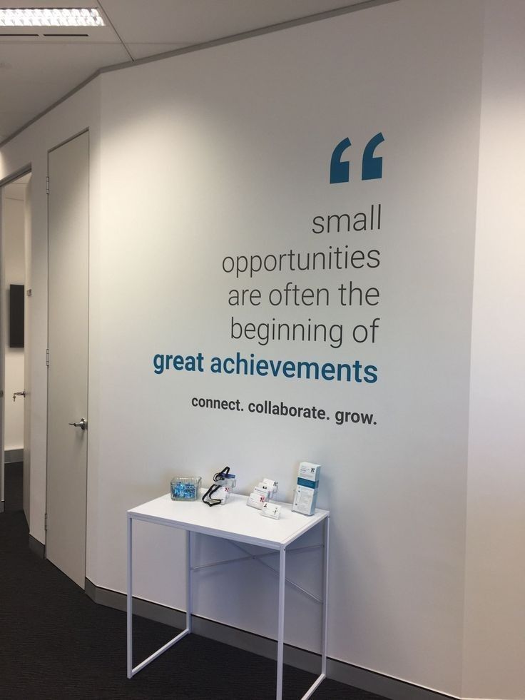 a white table sitting in front of a wall with a sign on it that says small opportunities are often the beginning of great achievement