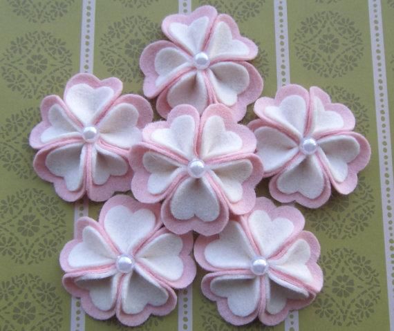 pink and white felt flowers with pearls on them sitting on a striped tablecloth background