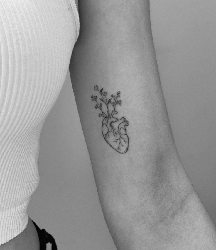 a heart tattoo with flowers on the arm