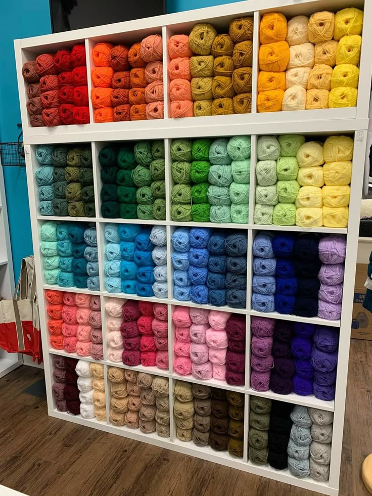 there are many different colors of yarn on the shelves