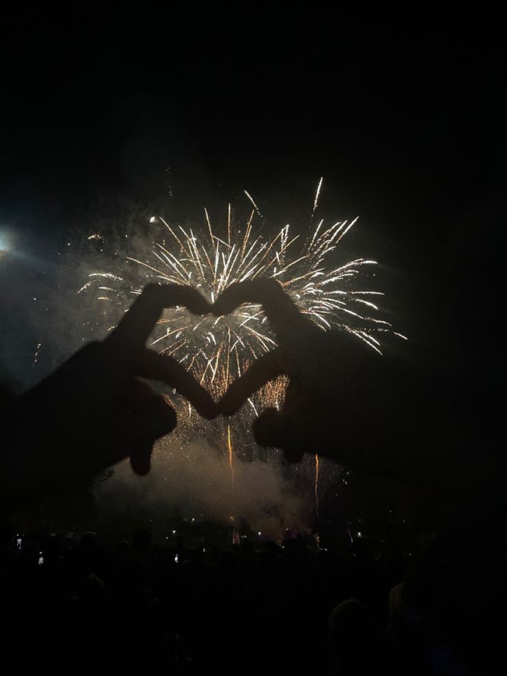 two people holding their hands in front of fireworks