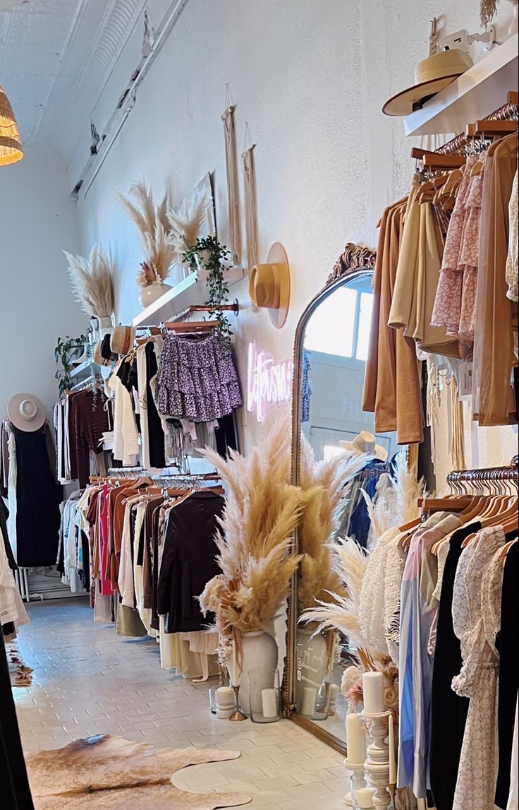 a clothing store filled with lots of clothes and other items on display in front of a mirror