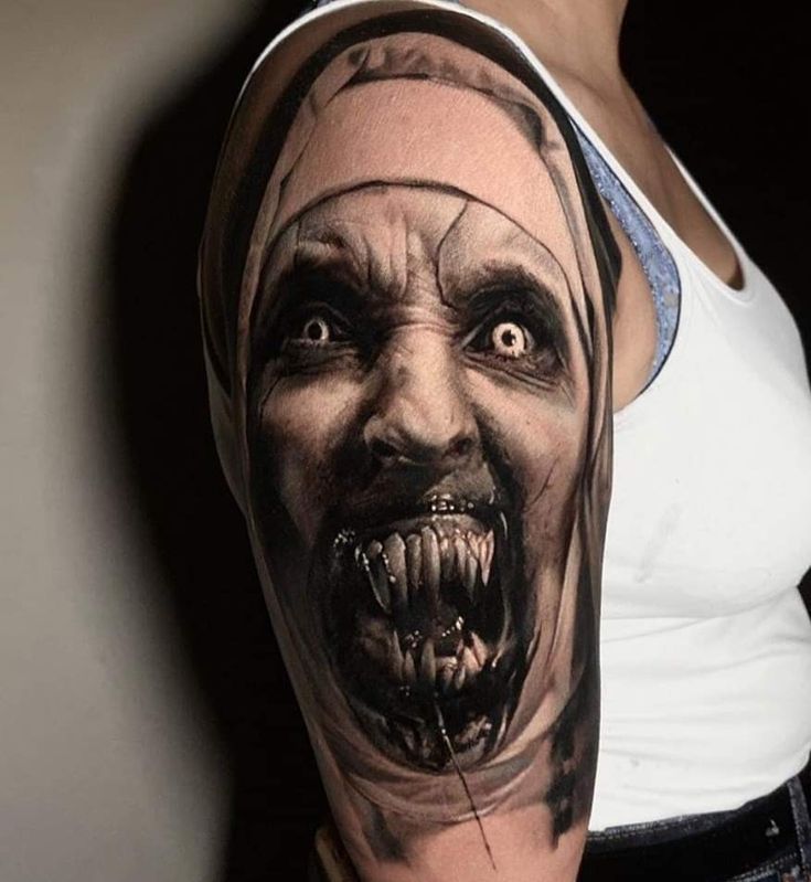 a woman with a scary face and head tattoo on her arm