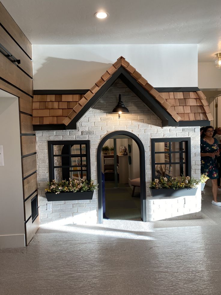 a doll house made out of fake bricks with windows and flowers in the window boxes