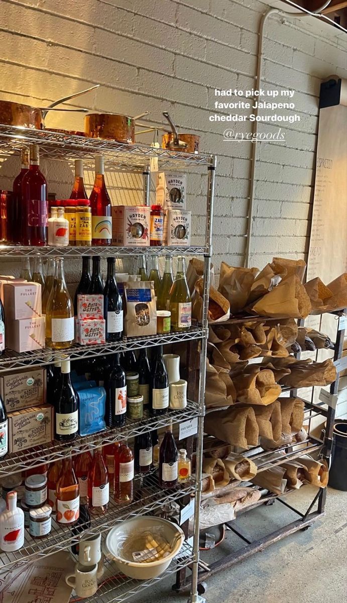 several shelves filled with different types of wine and condiments in front of a brick wall