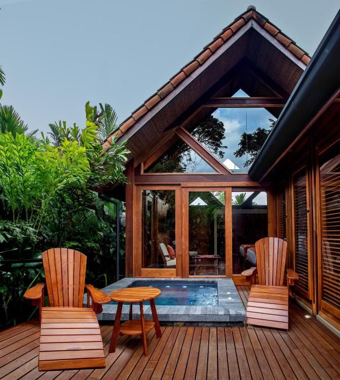 two wooden chairs sitting on top of a wooden deck next to a hot tub under a roof