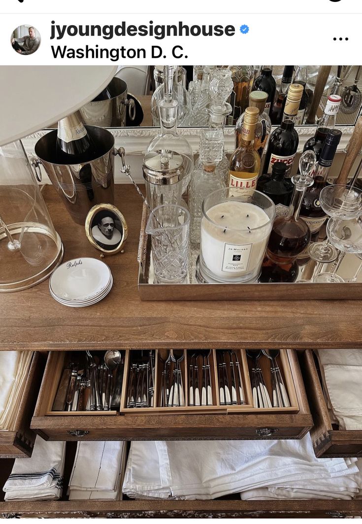 an open drawer with utensils and other items in it on top of a table