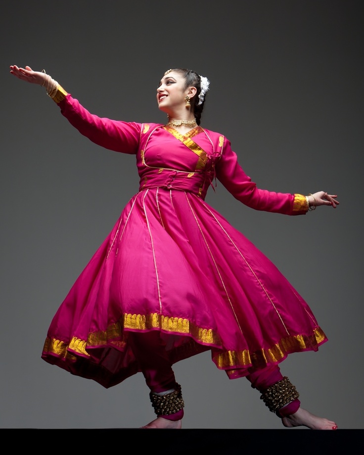 a woman in a pink and yellow dress is dancing with her arms out to the side