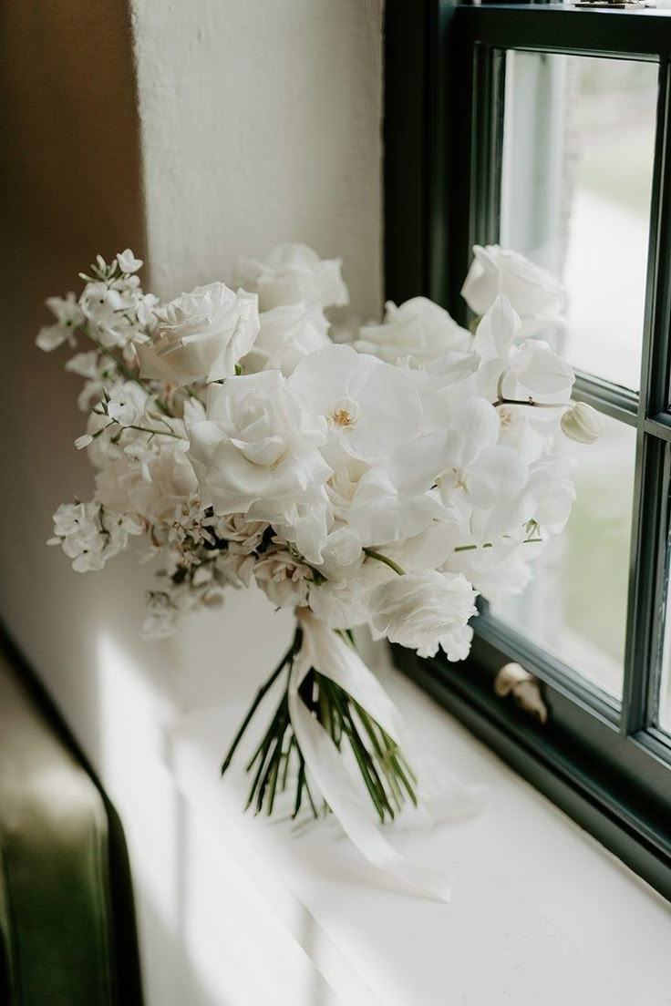 a bouquet of white flowers sitting on top of a window sill