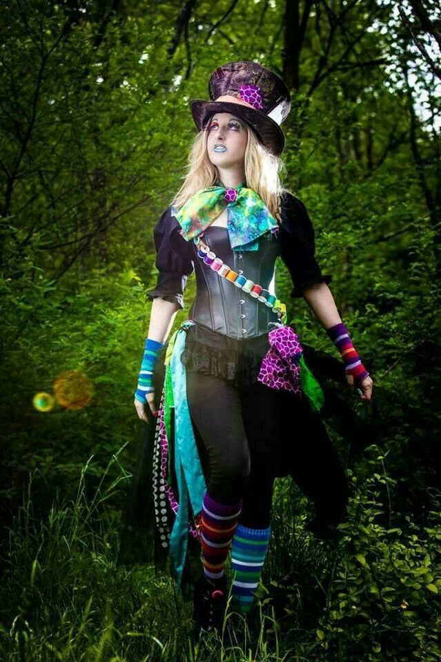 a woman dressed in costume is walking through the woods with her hat and gloves on