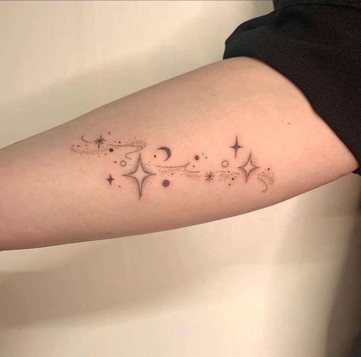 a woman's arm with stars and crescents on it, in black ink