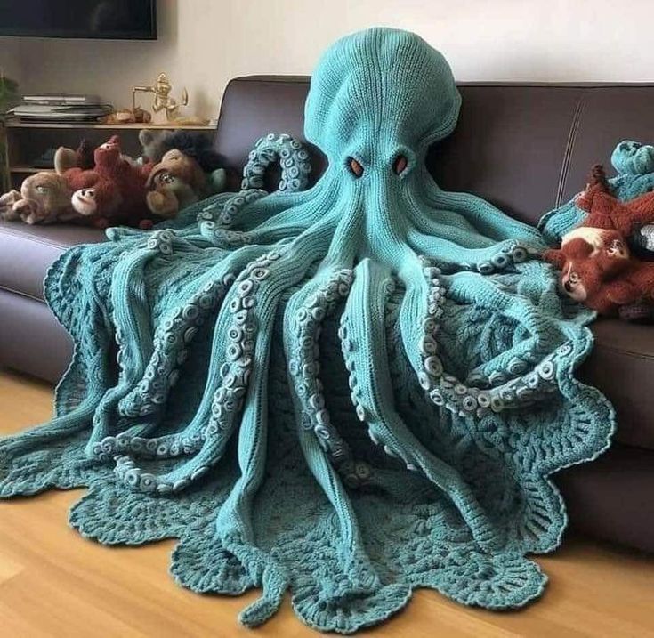 an octopus crocheted blanket sitting on top of a couch next to stuffed animals