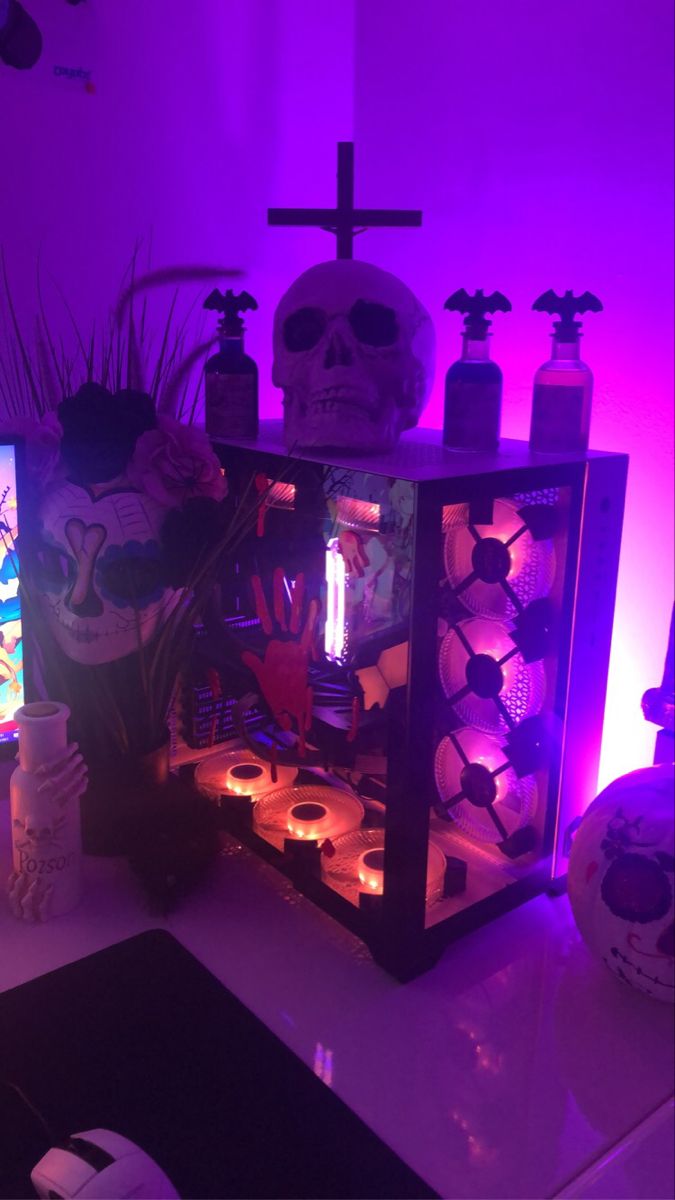 a table topped with candles and skulls in front of a purple light filled wall behind it