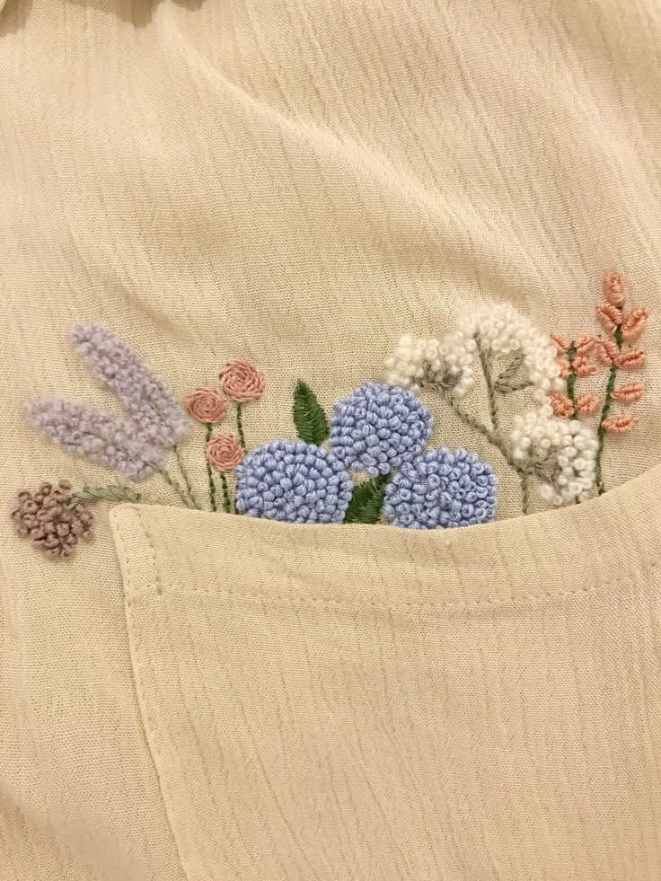 a close up of a person wearing a shirt with flowers embroidered on the back pocket