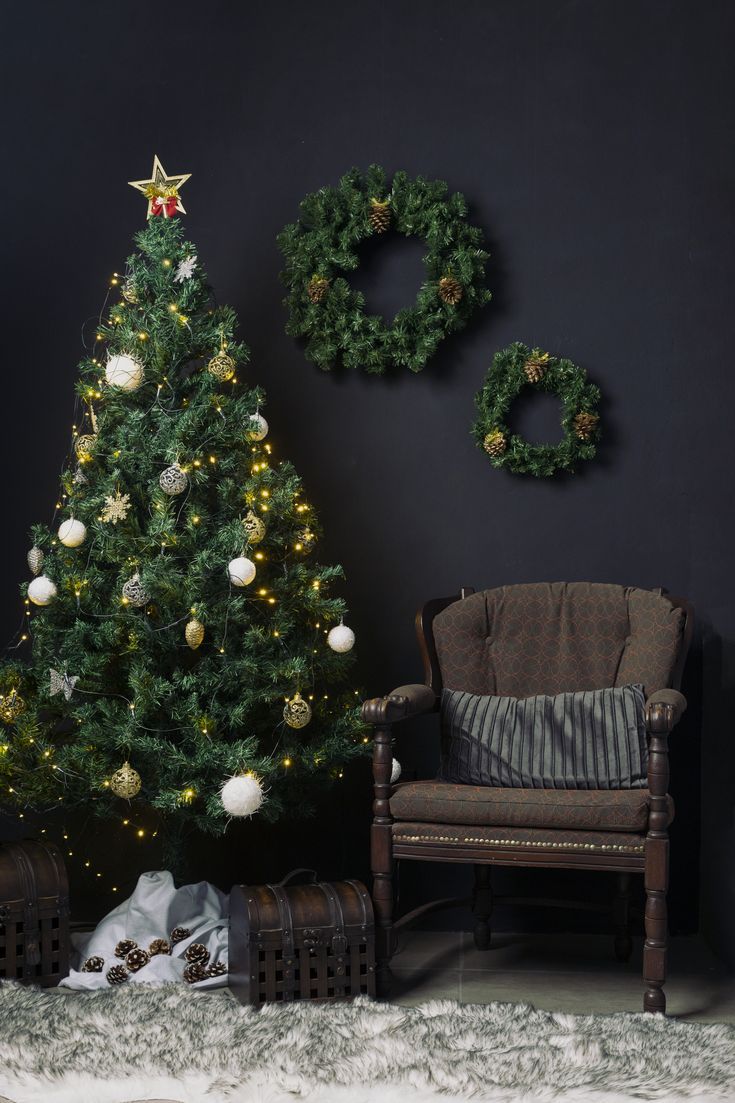 a living room with a christmas tree, chair and wreaths hanging on the wall