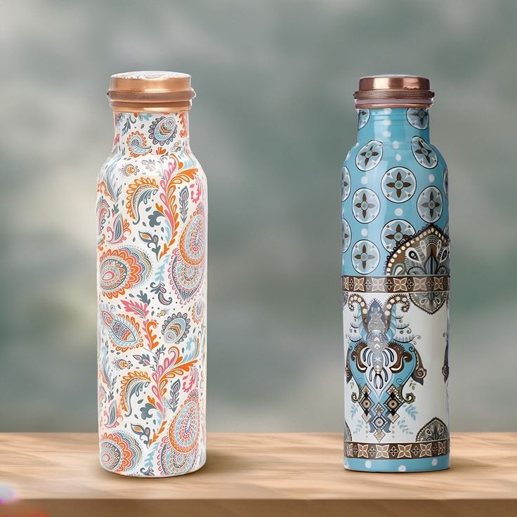 two vases sitting on top of a wooden table next to each other with paisley designs