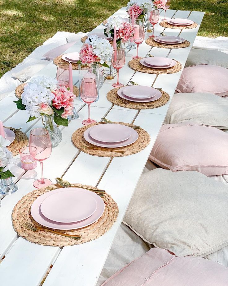 the table is set with pink and white plates, napkins, and vases