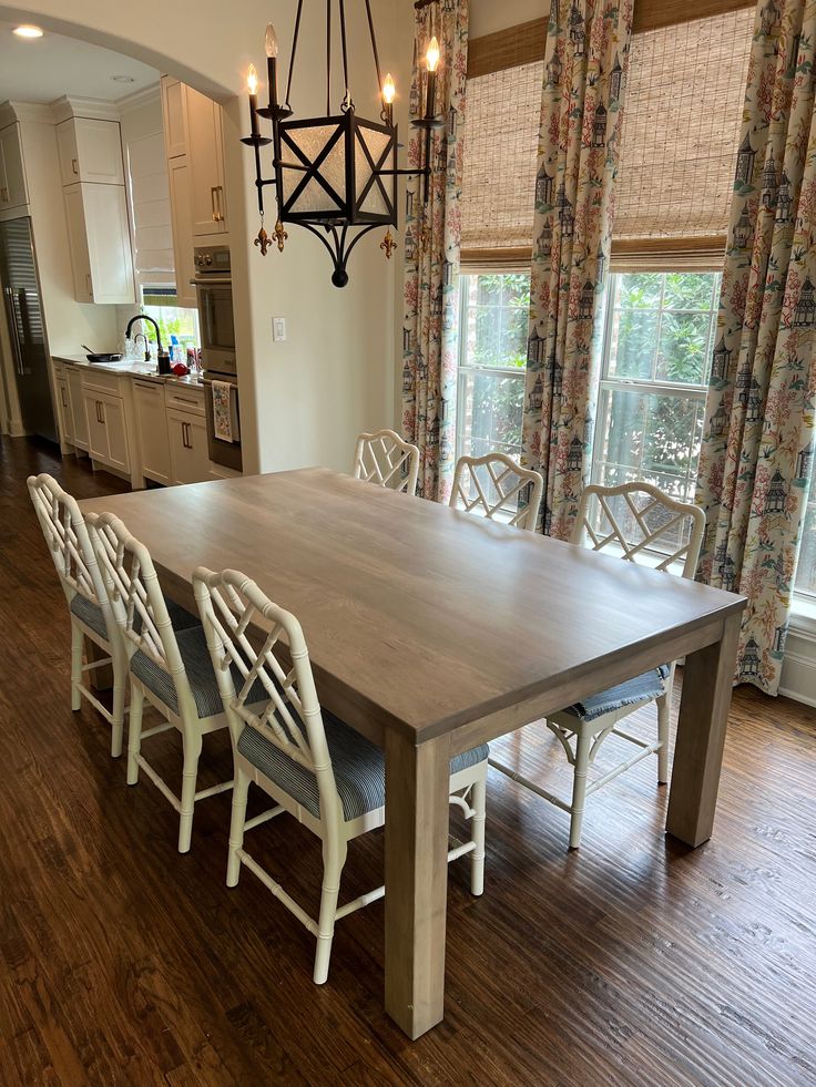 a dining room table with six chairs and a chandelier hanging from the ceiling