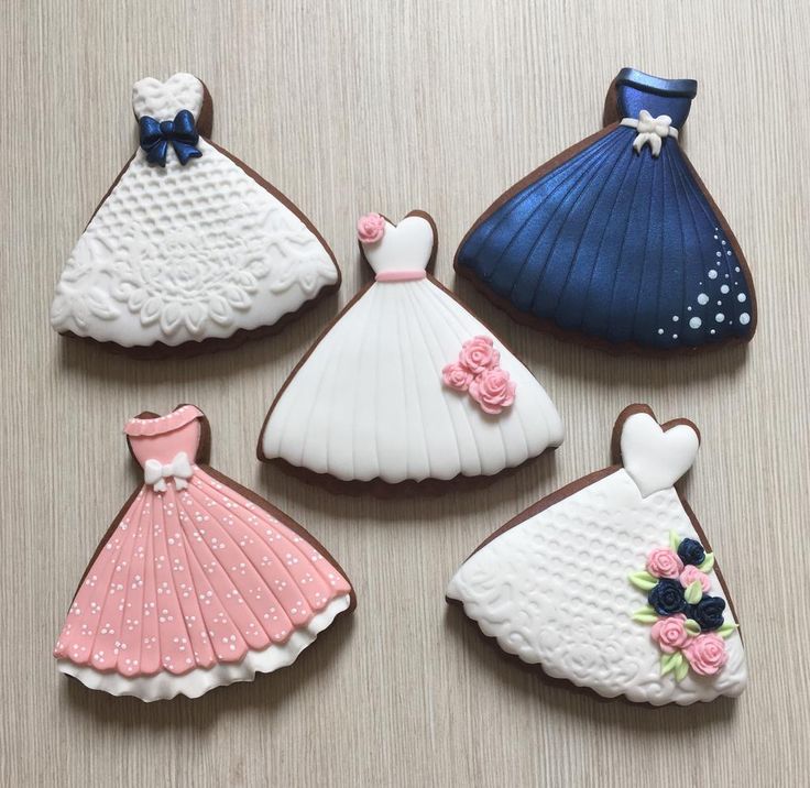 four decorated cookies in the shape of dresses