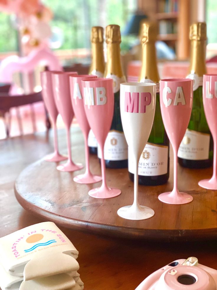 pink and white wine glasses with gold rims on a wooden table next to a camera