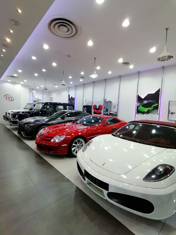 there are many cars in the showroom and one is red, white, and black