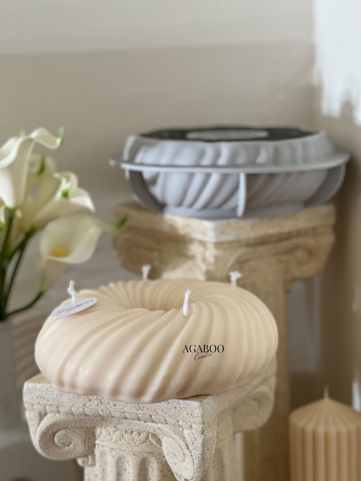 two white vases sitting next to each other on top of a table with candles