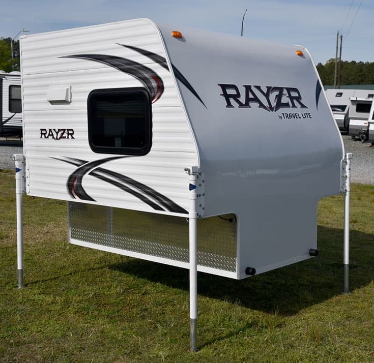 an rv parked in the grass near other vehicles