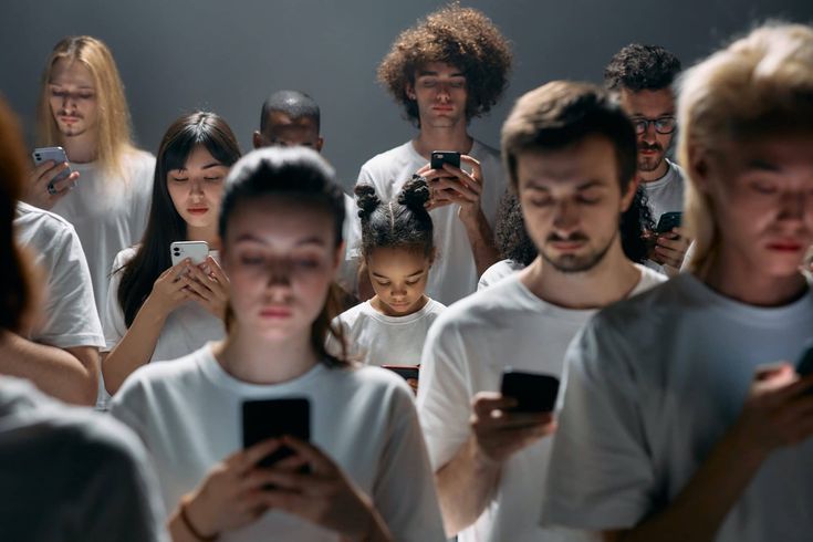 a group of people standing around each other with cell phones in their hands and looking at them