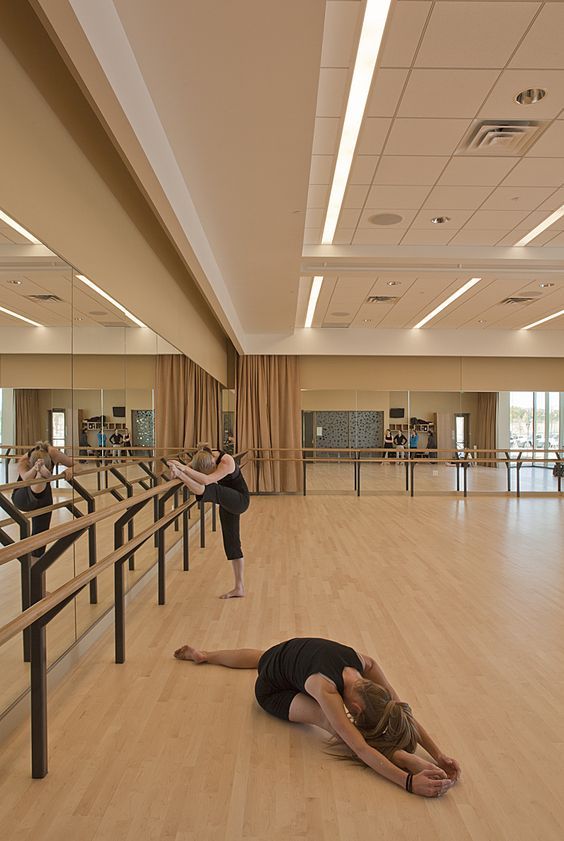 two people doing yoga on the floor in a large room with mirrors and railings