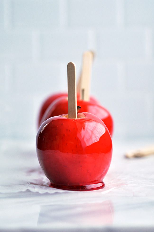 two red apples with toothpicks in them sitting on a table next to each other