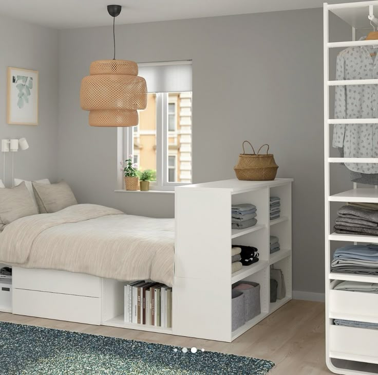 a white bed sitting next to a book shelf filled with lots of books on top of a hard wood floor