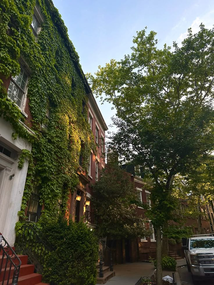 an apartment building covered in vines and ivy next to a car parked on the sidewalk