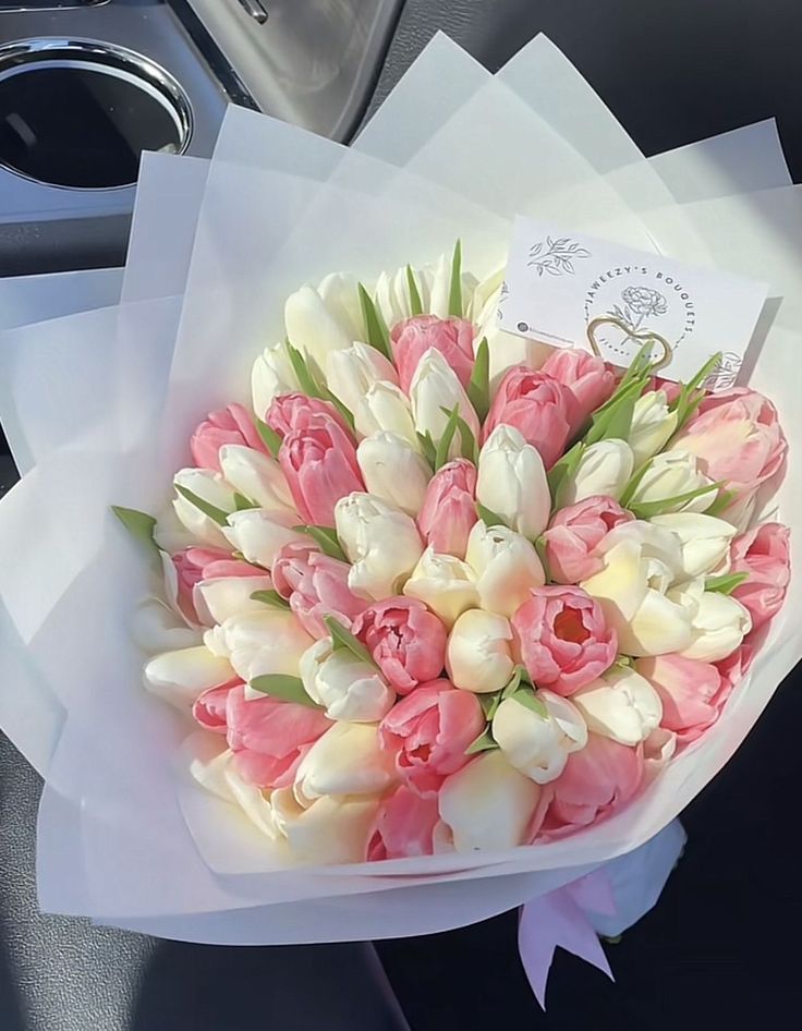 a bouquet of pink and white tulips in a car