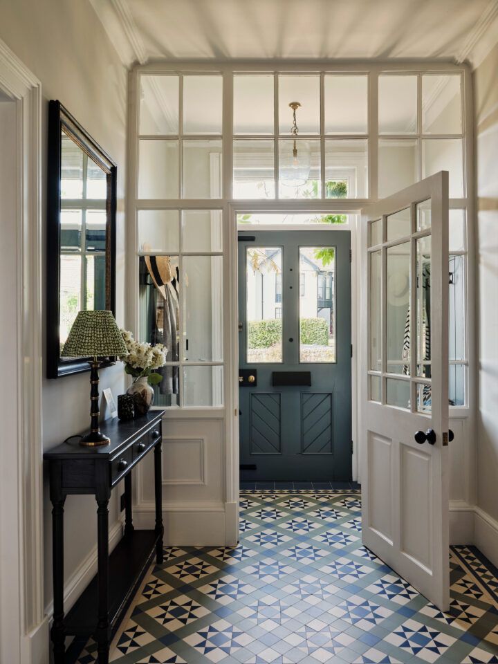 an entry way with blue and white tile flooring, two mirrors on either side of the door