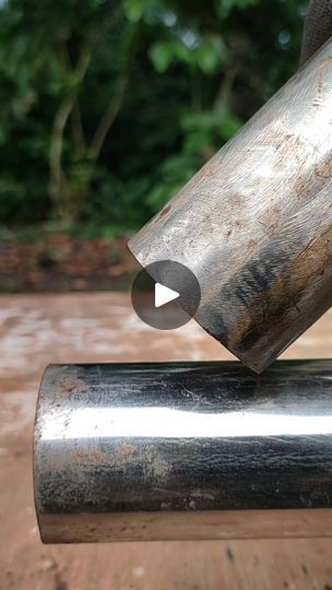 a close up of a metal object on a wooden surface with trees in the background