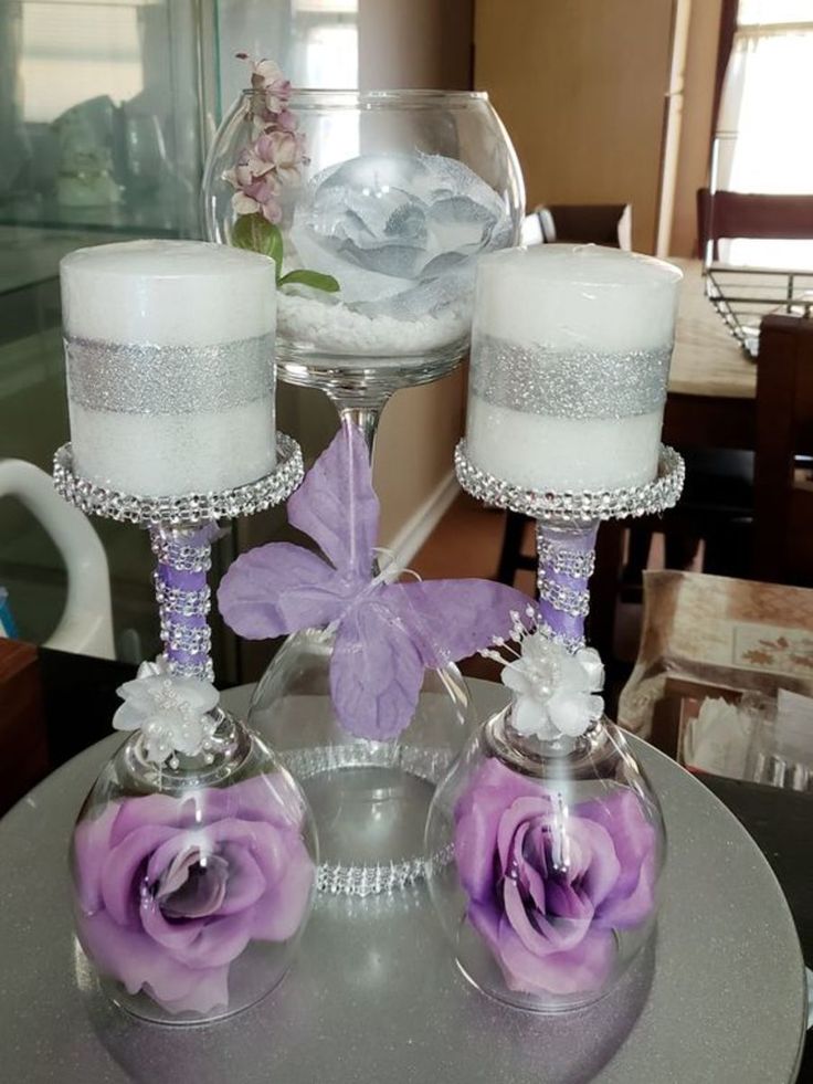 two wine glasses sitting on top of a table next to each other with flowers in them