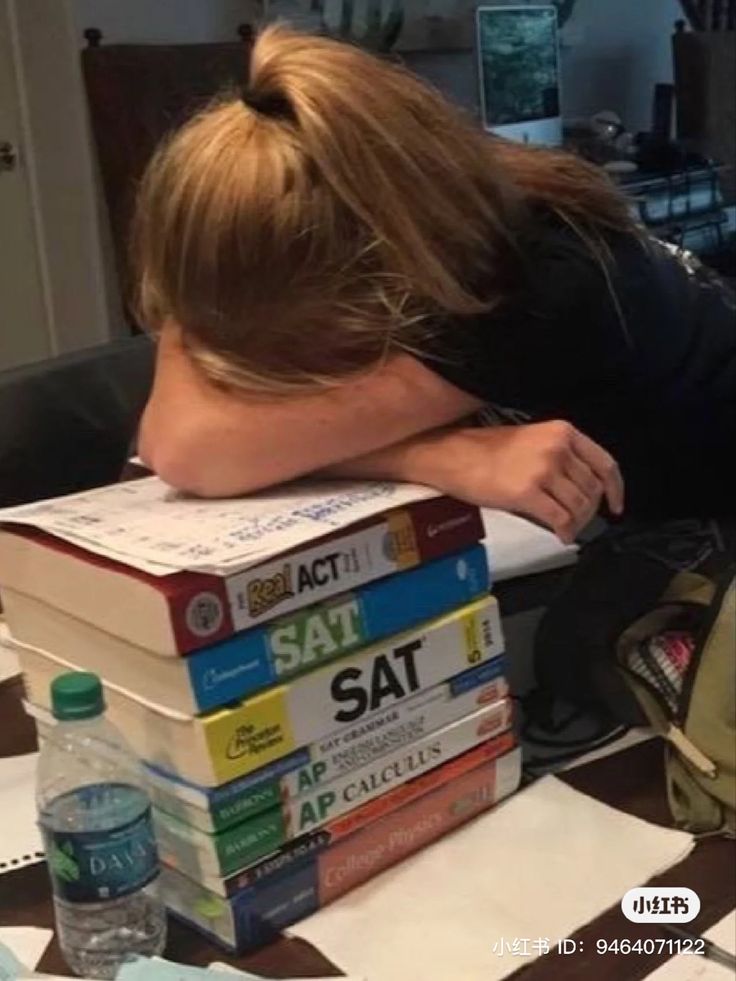 a woman leaning her head on a stack of books