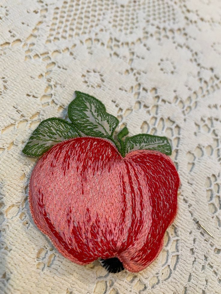 a red apple sitting on top of a white doily