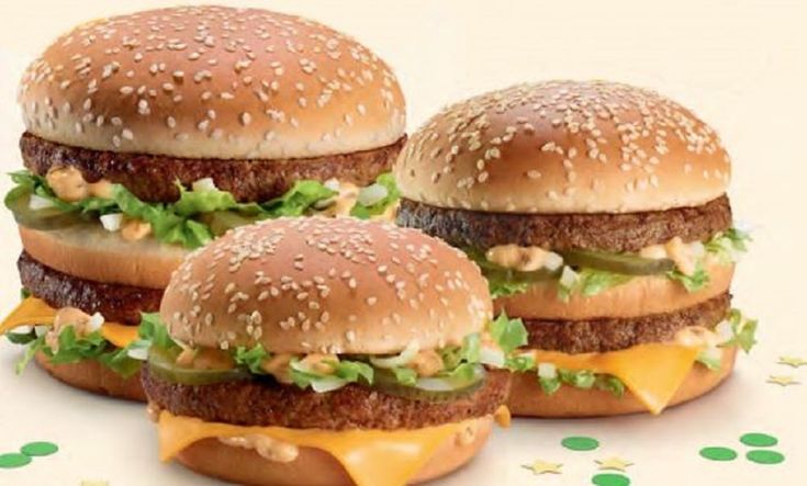 three hamburgers with cheese and lettuce on them sitting next to each other