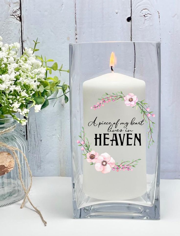 a white candle sitting next to a vase with flowers in it and a message on the front