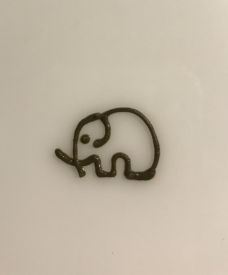 an elephant drawn on the side of a white plate with black writing that says elephant