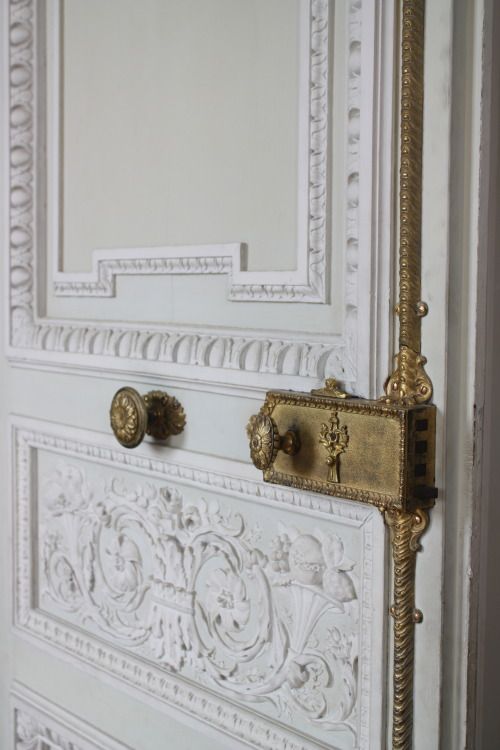 an ornate white door with gold handles and knobs