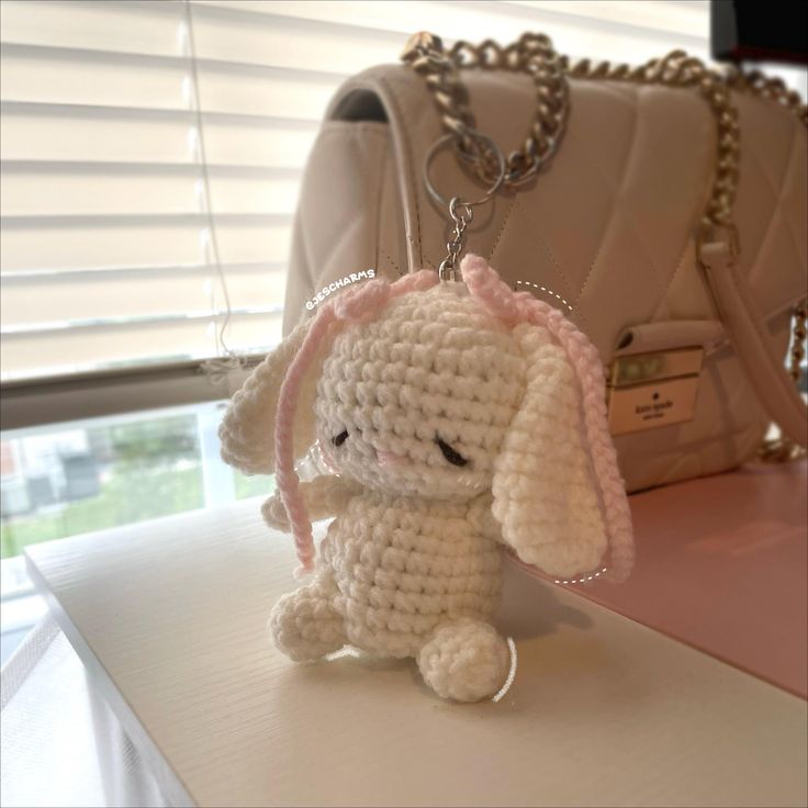 a crocheted bunny keychain sitting on top of a table next to a purse