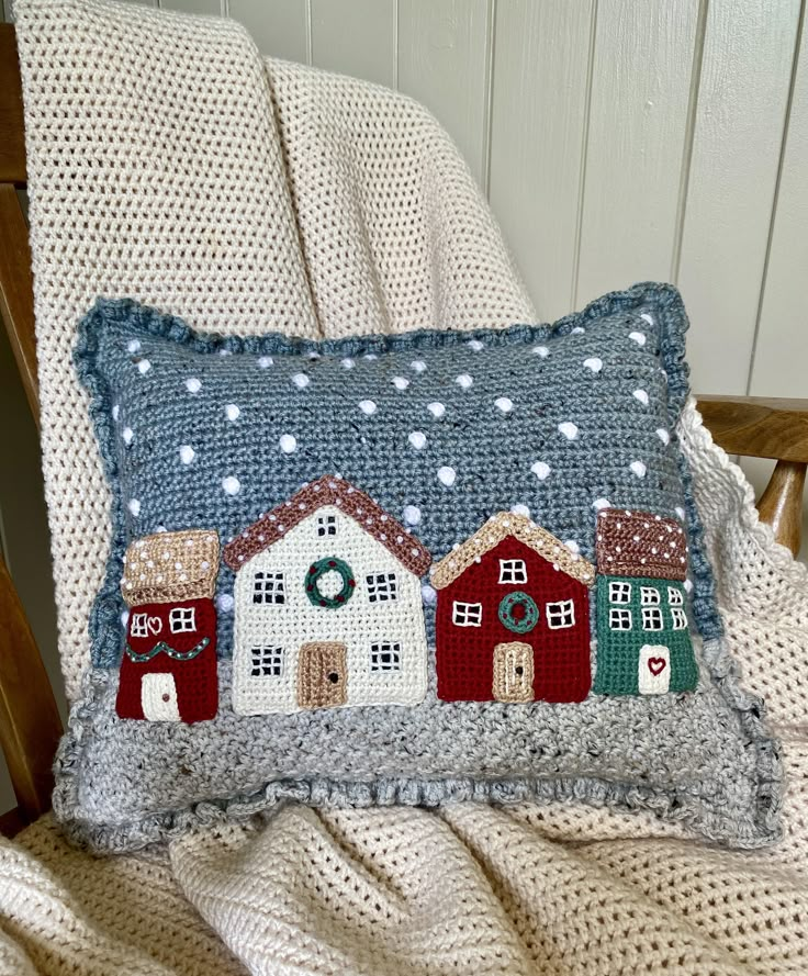 a pillow with houses on it sitting on a chair in front of a white wall